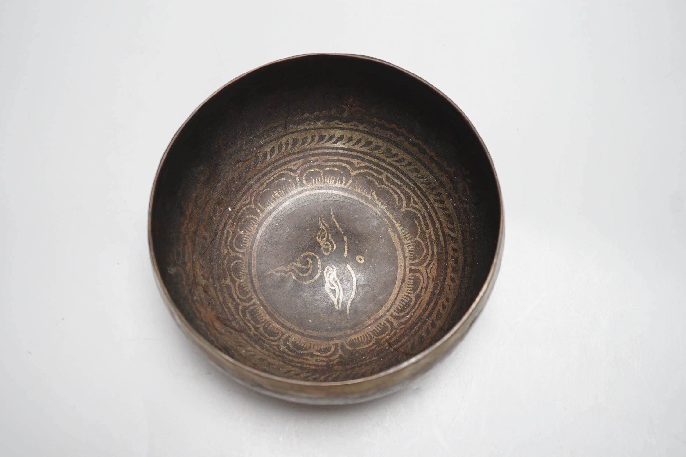 A bronze Nepalese temple bowl decorated with script, 18cm diameter